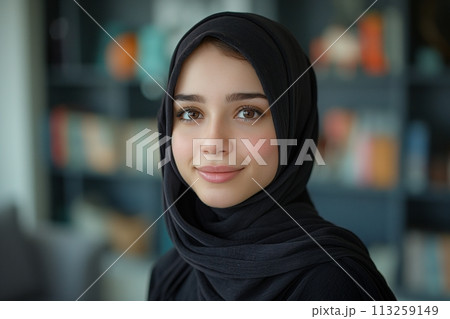 Portrait of young smiling Arabian muslim woman in black hijab on blurred background 113259149