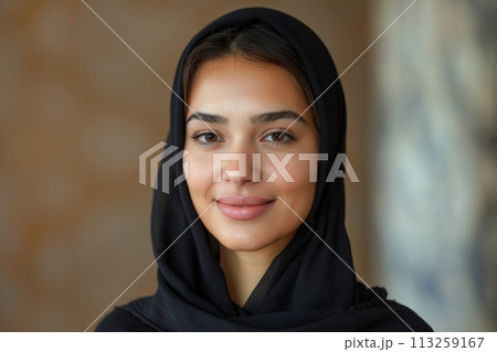Portrait of young smiling Arabian muslim woman in black hijab on blurred background 113259167
