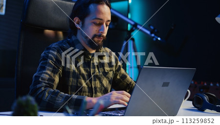 Portrait of smiling freelancer working from home, typing on laptop, surfing the net. Joyful remote employee browsing on digital device, sending emails to customers, camera B Portrait of smiling freelancer working from home, typing on laptop, surfing the net. Joyful remote employee browsing on digital device, sending emails to customers, camera B 113259852