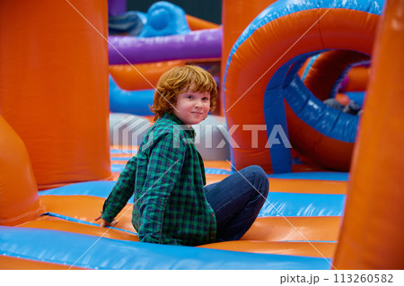 Cute boy playing on inflatable bounce house in entertainment center 113260582
