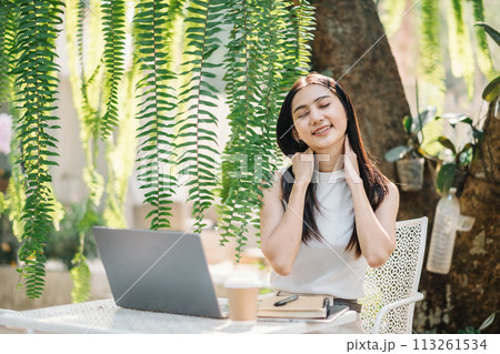 Woman takes a relaxing break from work, enjoying the tranquil environment of an outdoor garden cafe. Woman takes a relaxing break from work, enjoying the tranquil environment of an outdoor garden cafe. 113261534