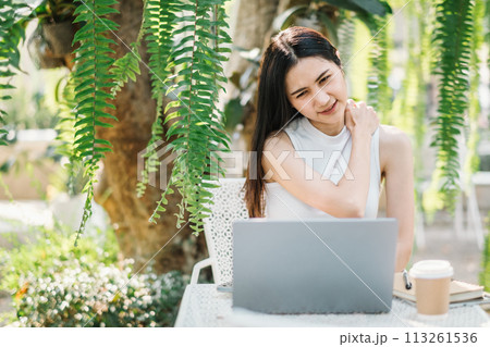 Woman takes a relaxing break from work, enjoying the tranquil environment of an outdoor garden cafe. 113261536