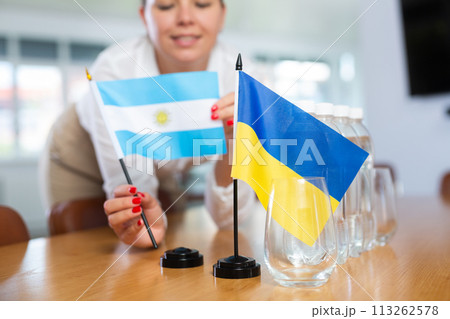 Office coordinator setting flags of Ukraine and Argentina on negotiating table 113262578