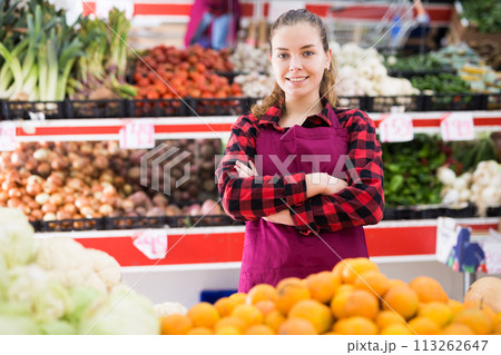 Friendly woman vegetable shop seller posing behind a counter Friendly woman vegetable shop seller posing behind a counter 113262647