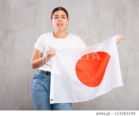 Irritated girl stands with flag of Japan. Isolated on gray background 113263144