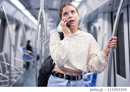 Portrait of woman holding smart phone in a subway train Portrait of woman holding smart phone in a subway train 113263304
