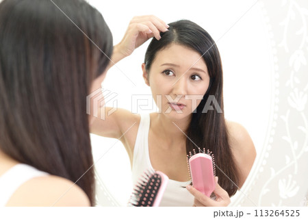 鏡を見てダメージヘアに悩む女性 113264525