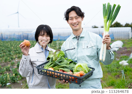 農作物を持つ農家の若い男女 113264678