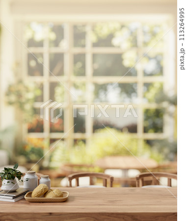A rustic wooden dining table in a beautiful dining room with a view from a garden on a sunny day. 113264995