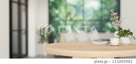 A space for display products on a minimalist round wooden table in a contemporary white living room. A space for display products on a minimalist round wooden table in a contemporary white living room. 113265001