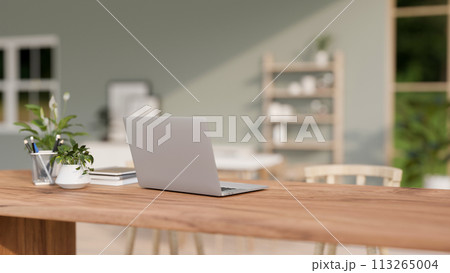 A back view of a laptop computer on a wooden table in a contemporary bright room. A back view of a laptop computer on a wooden table in a contemporary bright room. 113265004