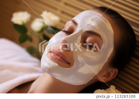 Beautiful brunette woman enjoying applying cosmetic mask with closed eyes 113265100