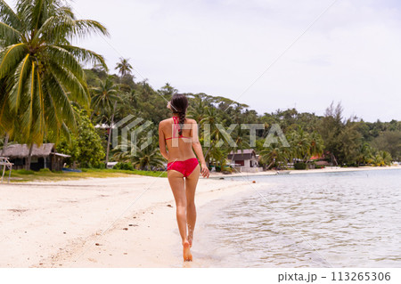 Beach Stroll Serenity: Woman in Red Bikini Walking on Matira Beach, Bora Bora, Tahiti, French Polynesia. This image is completely unretouched and model is with no makeup. Raw Image Beach Stroll Serenity: Woman in Red Bikini Walking on Matira Beach, Bora Bora, Tahiti, French Polynesia. This image is completely unretouched and model is with no makeup. Raw Image 113265306