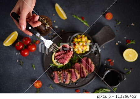 Sliced Organic grilled Tuna fillet covered with sesame seeds and mango salsa on black ceramic serving board 113266452