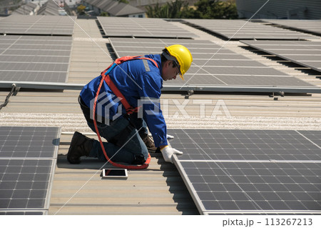 Engineers install solar cells on the roof of factory 113267213
