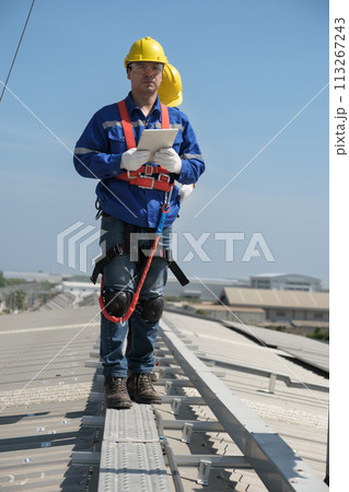 Engineers install solar cells on the roof of factory 113267243