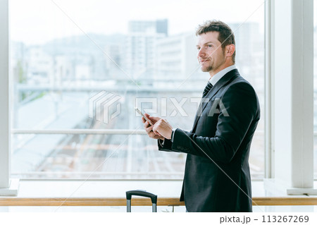 駅・ターミナルでスマホを操作するスーツ姿の外国人ビジネスマン 113267269