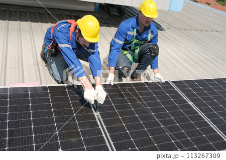 Engineers install solar cells on the roof of factory 113267309