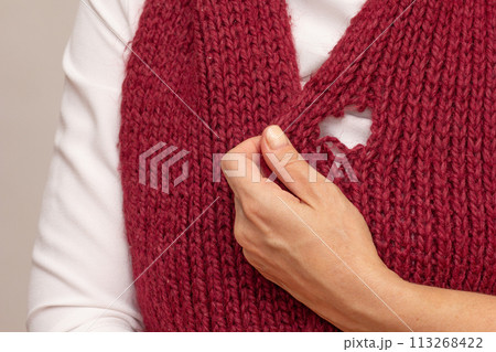 Woman hand holding knitted thing with hole made by moth 113268422