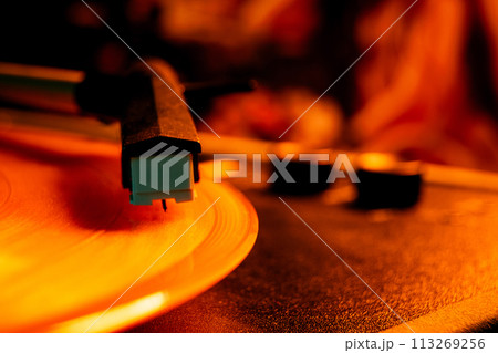 Stylus gently resting on grooves of spinning record in warm, golden light. Vinyl record player, bright lights disco-bokeh. Stylus gently resting on grooves of spinning record in warm, golden light. Vinyl record player, bright lights disco-bokeh. 113269256