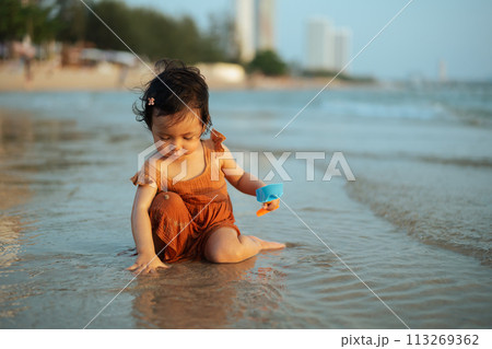 happy toddler baby girl playing toy and water on sea beach happy toddler baby girl playing toy and water on sea beach 113269362