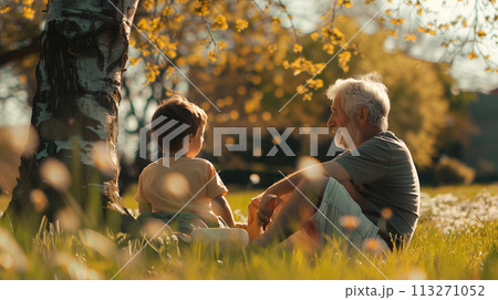 Grandfather and grandson sitting under a tree in autumn Grandfather and grandson sitting under a tree in autumn 113271052
