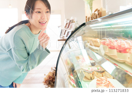 ショーウィンドウ内のケーキを選ぶ若い女性 113271833