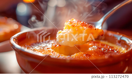 A classic Creme brulee, served in a ramekin, with a spoon breaking through the caramelized surface of the dessert. 113272470