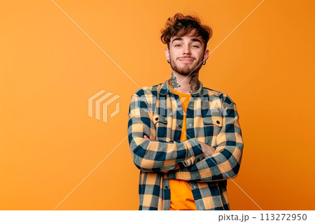 A man with tattoos on his arm and a beard is standing in front of a yellow wall 113272950