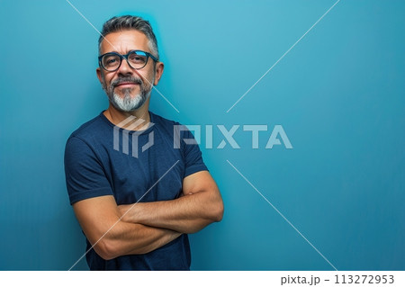 A man with glasses is smiling and standing in front of a blue wall 113272953