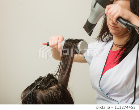 Hairdresser styling woman dark long hair Hairdresser styling woman dark long hair 113274458