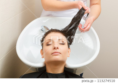 Hairdresser washing her woman customer hair Hairdresser washing her woman customer hair 113274510