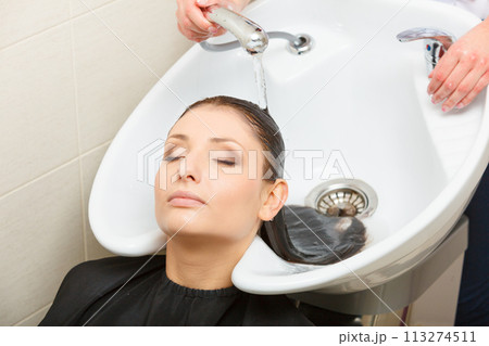 Hairdresser washing her woman customer hair Hairdresser washing her woman customer hair 113274511