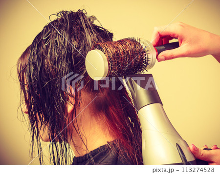 Hairdresser styling woman dark long hair Hairdresser styling woman dark long hair 113274528