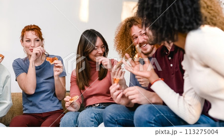 Happy woman looking at anonymous friends while enjoying pizza party at home 113275004