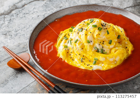 Delicious Asian tornado omelette with sesame seeds, green onions and hot pepper sauce close-up in a plate. Horizontal 113275457