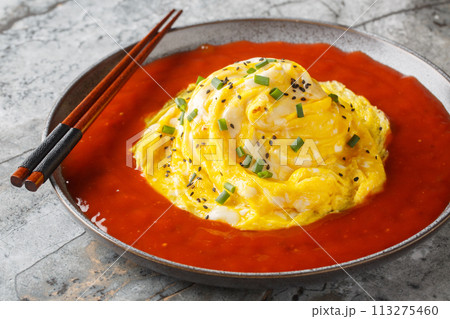 Asian swirl omelette tornado with fried rice and hot sauce close-up in a plate. Horizontal 113275460