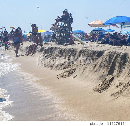 Group of People Standing in front of lifeguards on Sandy Beach at the ocean Group of People Standing in front of lifeguards on Sandy Beach at the ocean 113276154