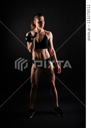 Tough fitness female model with kettle bell on grey dark yellow red background. 113278511