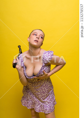 Beautiful seductive female holding hammer, isolated on yellow and red 113278537