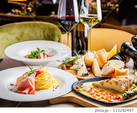 レストランのテーブルに並んだ料理とワイン、イタリアン レストランのテーブルに並んだ料理とワイン、イタリアン 113280497
