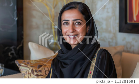 Middle aged middle Eastern woman sitting at home on couch, indoor portrait Middle aged middle Eastern woman sitting at home on couch, indoor portrait 113281691