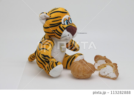 A toy tiger sits in front of sweets. Diet violation. Weight control. A toy tiger sits in front of sweets. Diet violation. Weight control. 113282888