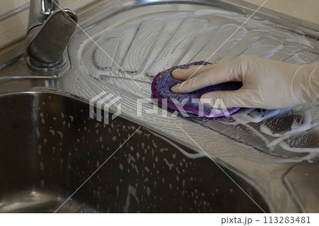 A woman in rubber gloves cleans the sink with detergent. House cleaning. A woman in rubber gloves cleans the sink with detergent. House cleaning. 113283481