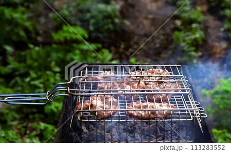 Shish kebab is fried on the grill. Food cooked on fire. Shish kebab is fried on the grill. Food cooked on fire. 113283552
