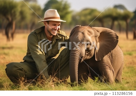 A man is holding a baby elephant in his arms 113286156