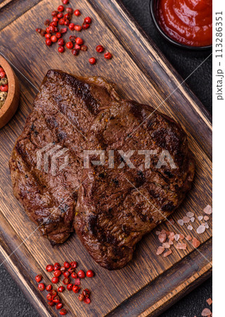 Fresh juicy delicious beef steak on a dark background Fresh juicy delicious beef steak on a dark background 113286351