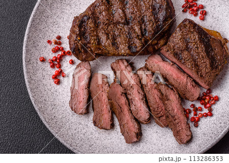Fresh juicy delicious beef steak on a dark background 113286353