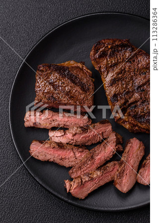 Fresh juicy delicious beef steak on a dark background Fresh juicy delicious beef steak on a dark background 113286364