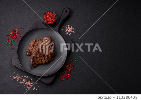 Fresh juicy delicious beef steak on a dark background Fresh juicy delicious beef steak on a dark background 113286438